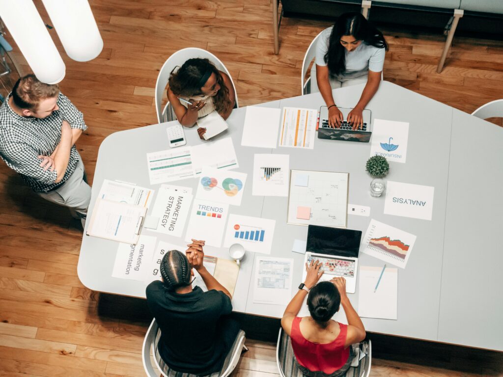 A diverse group working on technical seo audit with charts and laptops in an office setting.